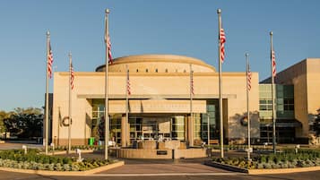 The exterior of the George Bush Library and Museum with a circular entrance, American flags, and a Christmas wreath.