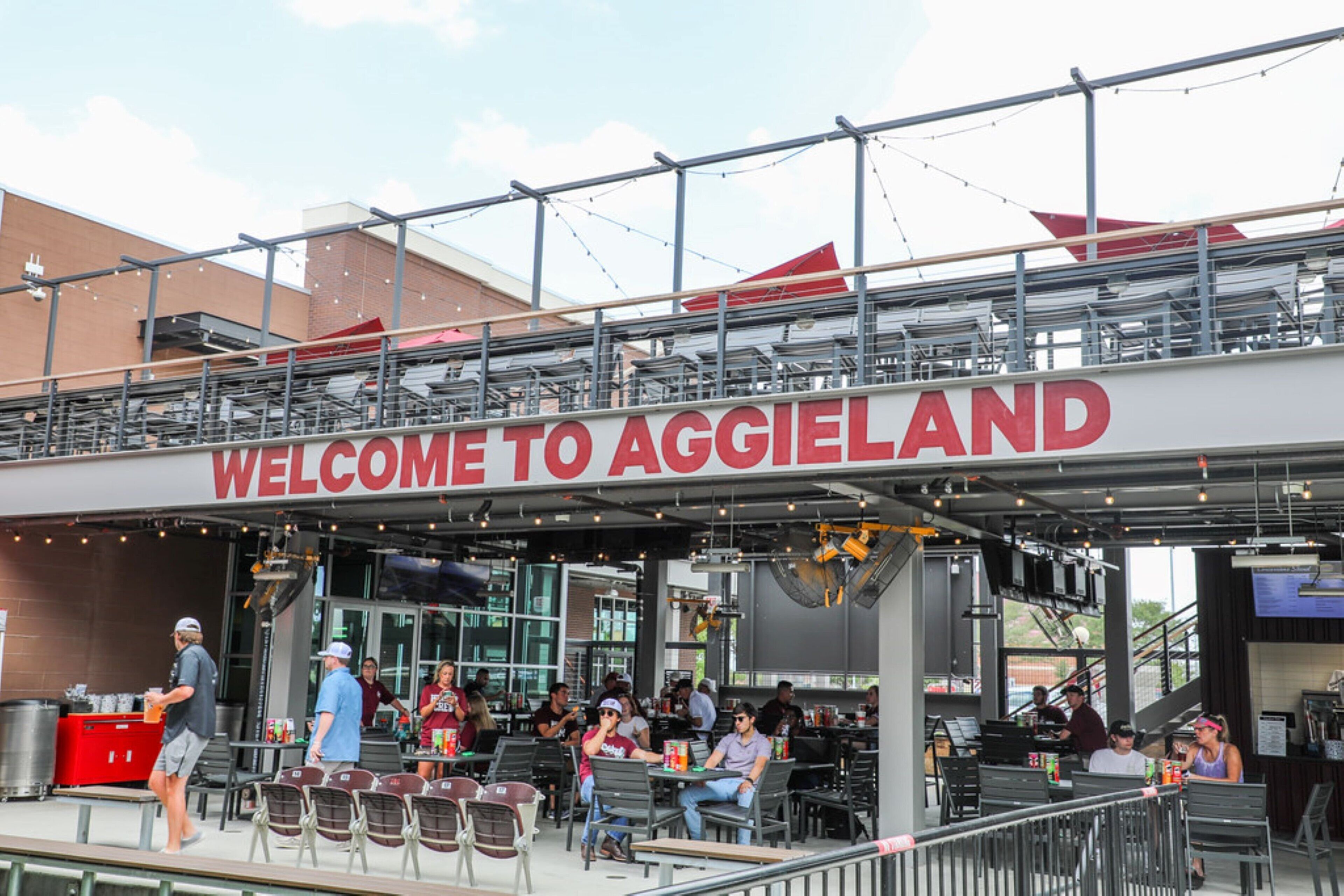 An outdoor seating area with a 'Welcome to Aggieland' sign above.