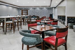 A modern restaurant interior with multiple dining tables and chairs, a patterned wall, and a clean, well-lit environment. - Holiday Inn & Suites College Station - Aggieland by IHG (College Station)