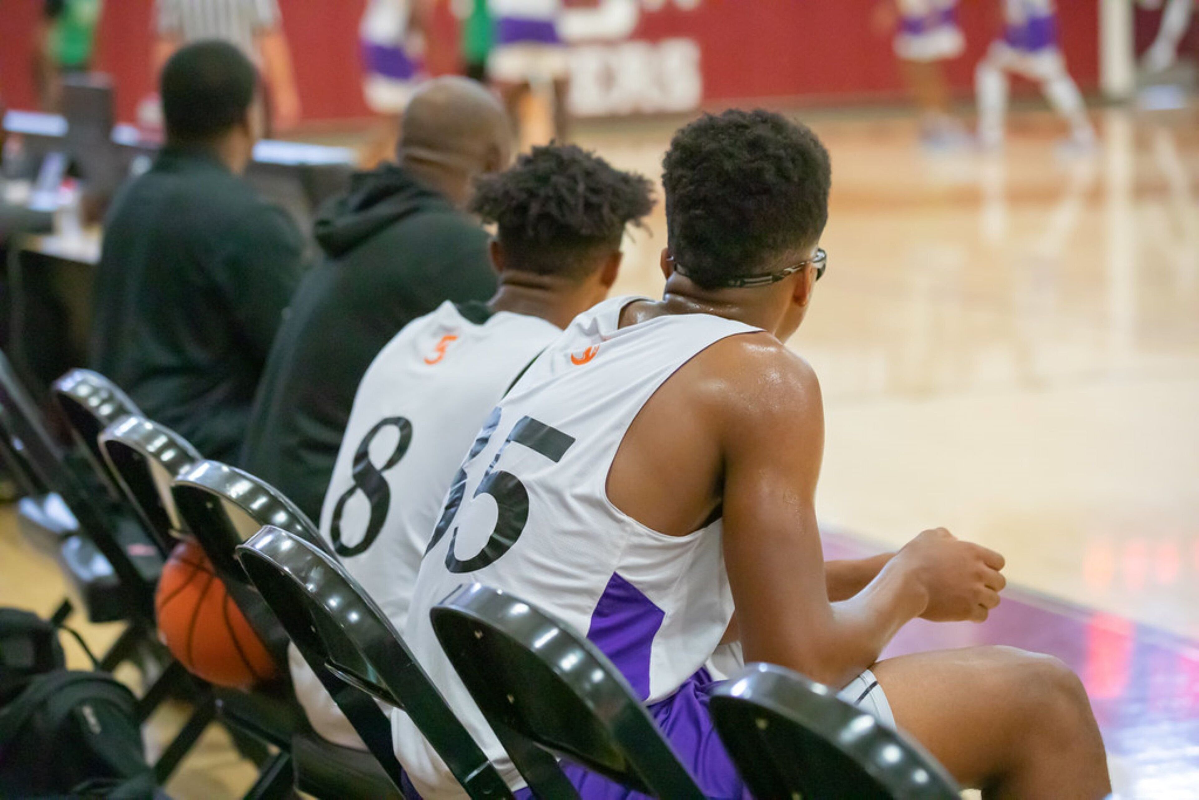 A basketball player sitting on a bench with a basketball.