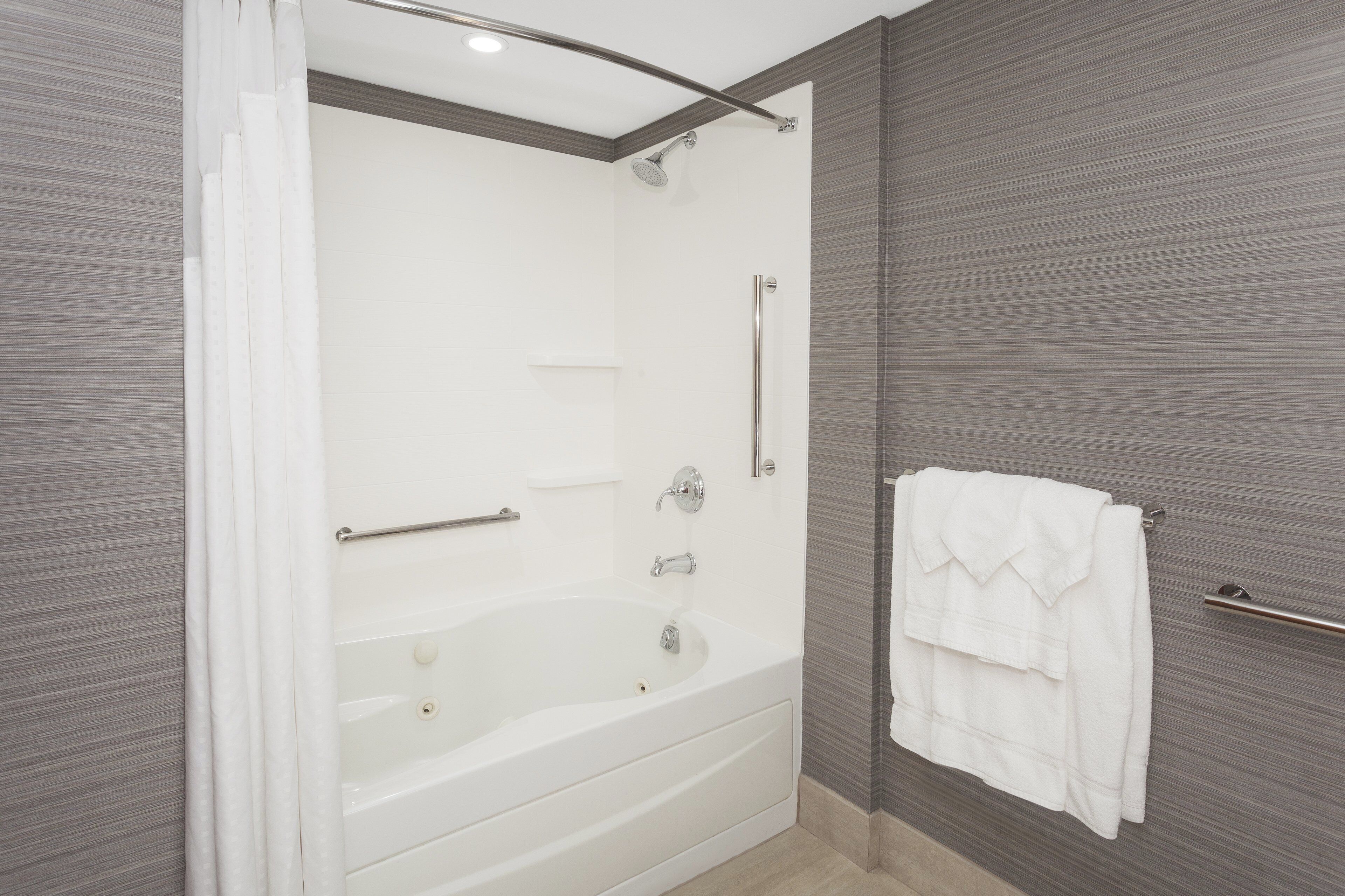 Un baño moderno con ducha a nivel, bañera y toallero.