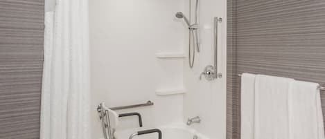 A bathroom with a white bathtub, a shower, and a grab bar.