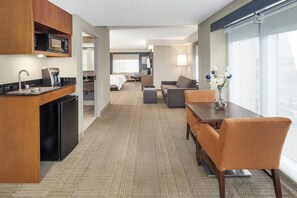 A hotel room with a kitchenette, a dining area, a sofa, and a bed. - Holiday Inn Express & Suites Riverhead - Long Island by IHG (Riverhead)