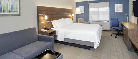 Una habitación de hotel con cama, escritorio, silla, sofá y ventana.