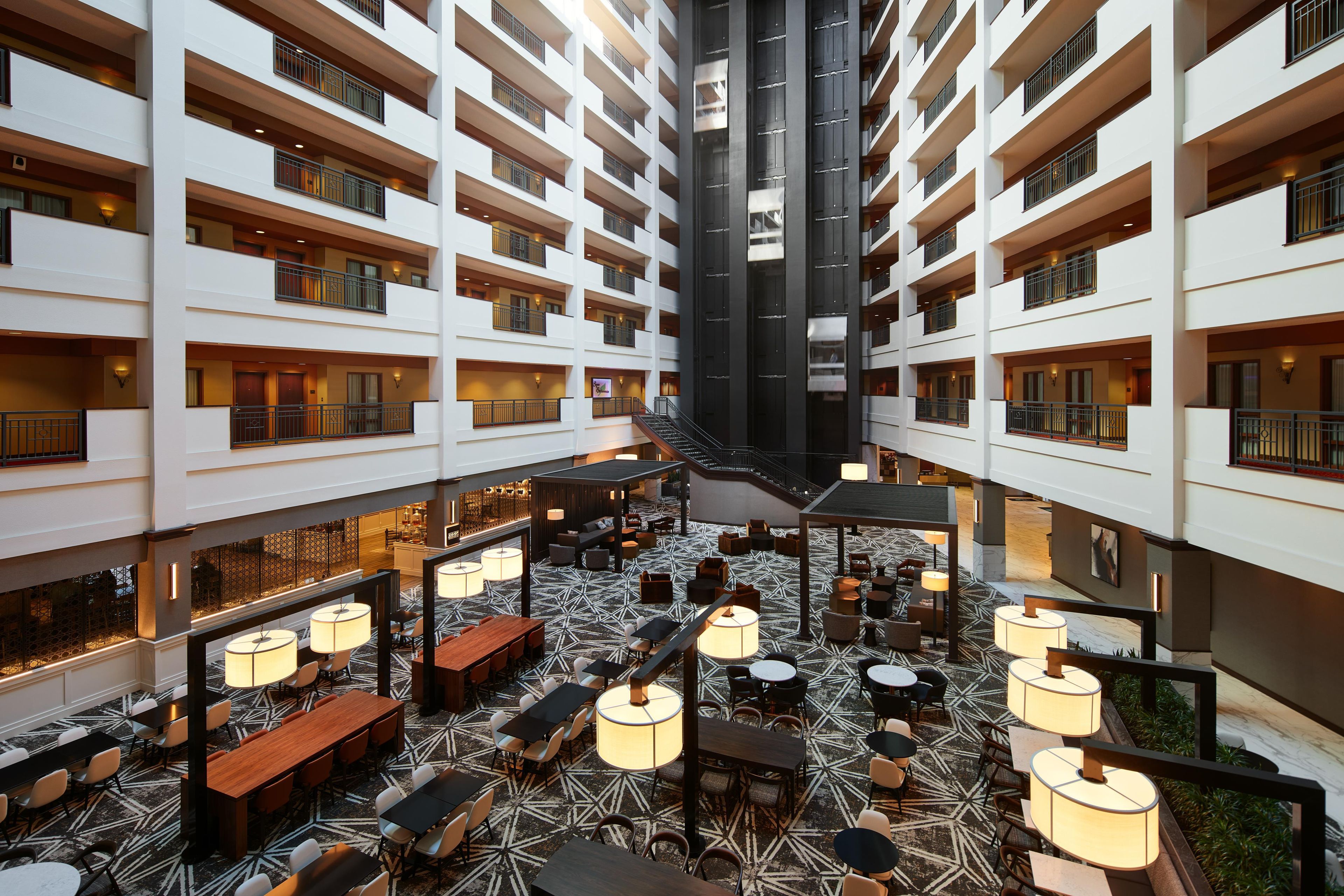 A multi-level hotel lobby with a central atrium, multiple dining areas, and balconies.