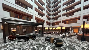 Een meerlaagse hotellobby met een vloer met een geometrisch patroon, zithoeken en een modern ontwerp.