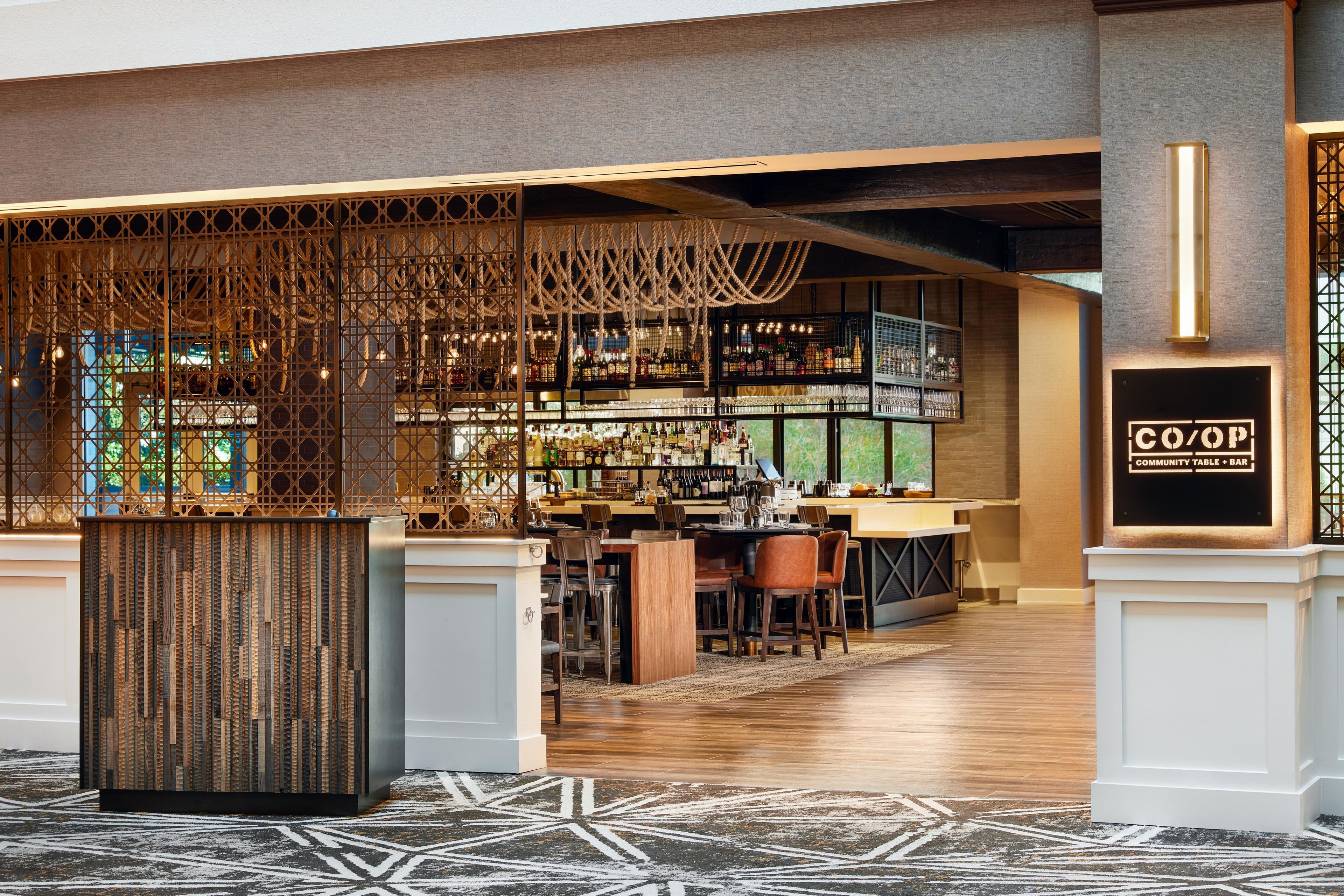 Un espace bar avec un plafond haut, des poutres en bois et une variété de bouteilles et de verres.