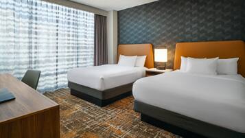 A hotel room with two beds, a desk, and a patterned carpet.