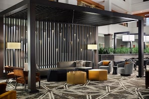 Ein stilvoller Lounge-Bereich mit Sitzgelegenheiten, einem gemusterten Teppich und einem dekorativen Raumteiler.