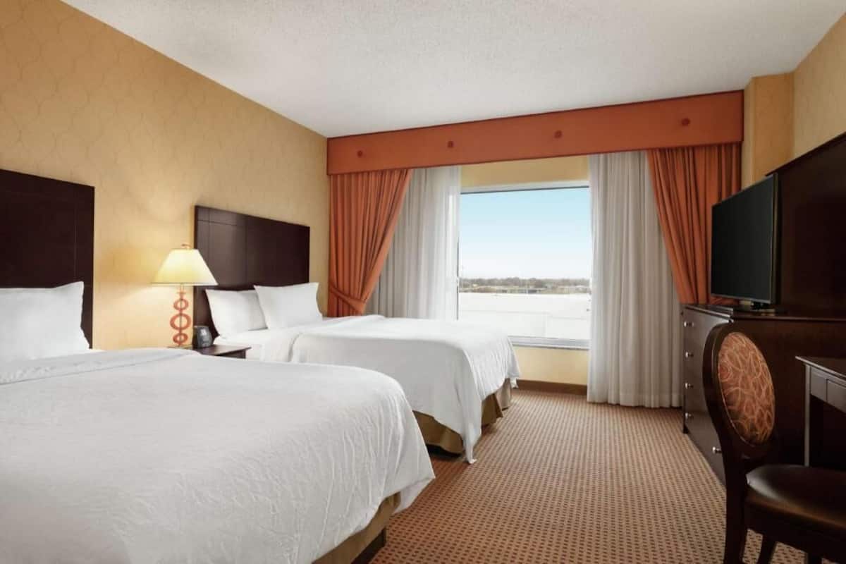 Une chambre d’hôtel avec deux lits, une télévision, un bureau et une vue sur l’extérieur.