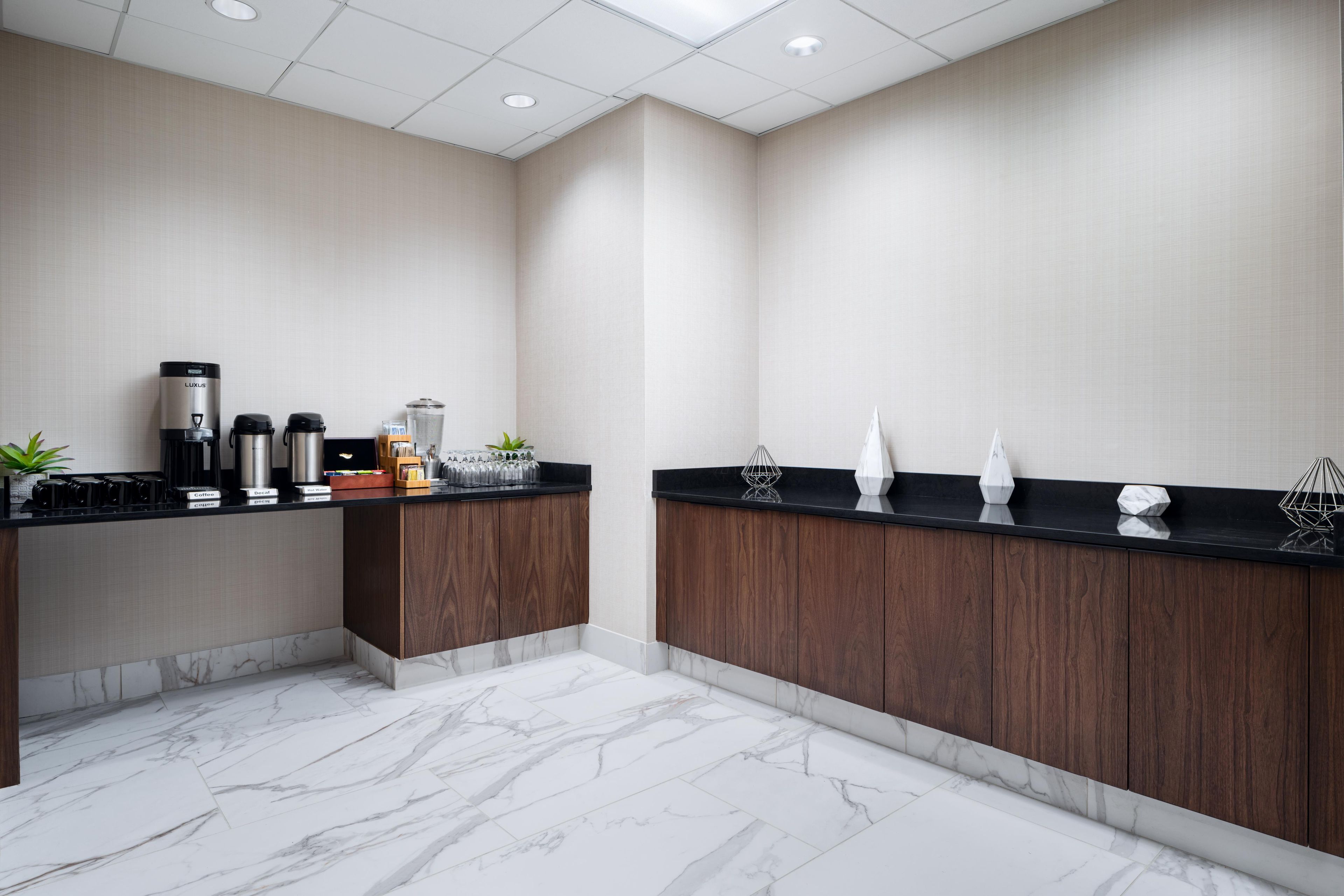 Una cocina moderna con piso de mármol, gabinetes de madera y una estación de café.