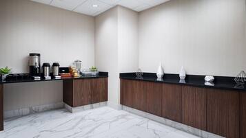 A modern kitchen with marble flooring, wooden cabinets, and a coffee station.