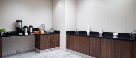 Una cocina moderna con piso de mármol, gabinetes de madera y una estación de café.