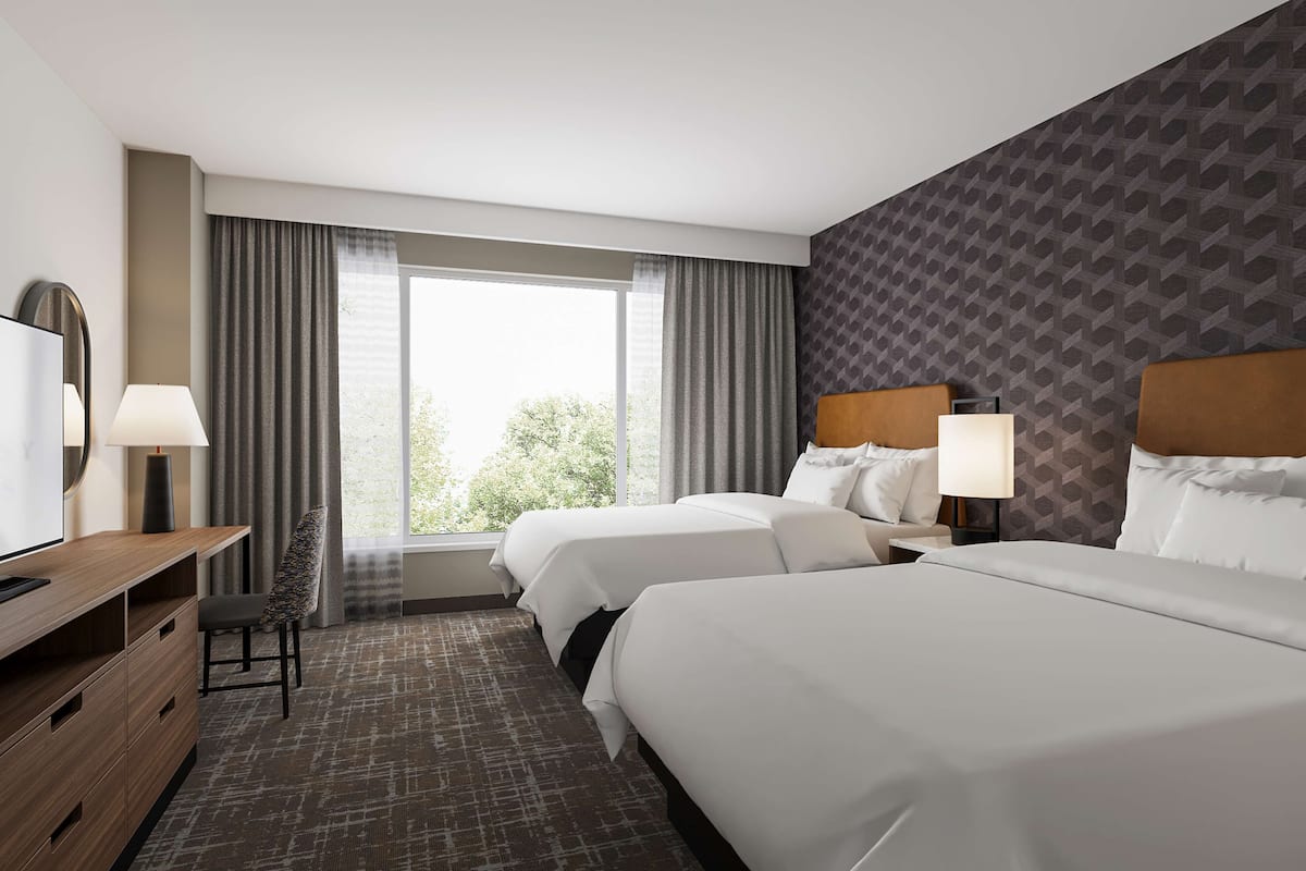 Une chambre d’hôtel avec deux lits, un bureau avec une chaise, une télévision et une grande fenêtre avec des rideaux.