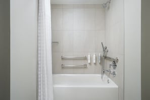Een moderne badkamer met een bad, handgrepen en toiletartikelen.