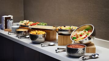 A buffet setup with various food items and utensils.