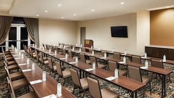 A conference room with multiple tables, chairs, and water bottles.