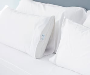 Een wit bed met kussens, waarvan er één het label 'Pure' heeft.