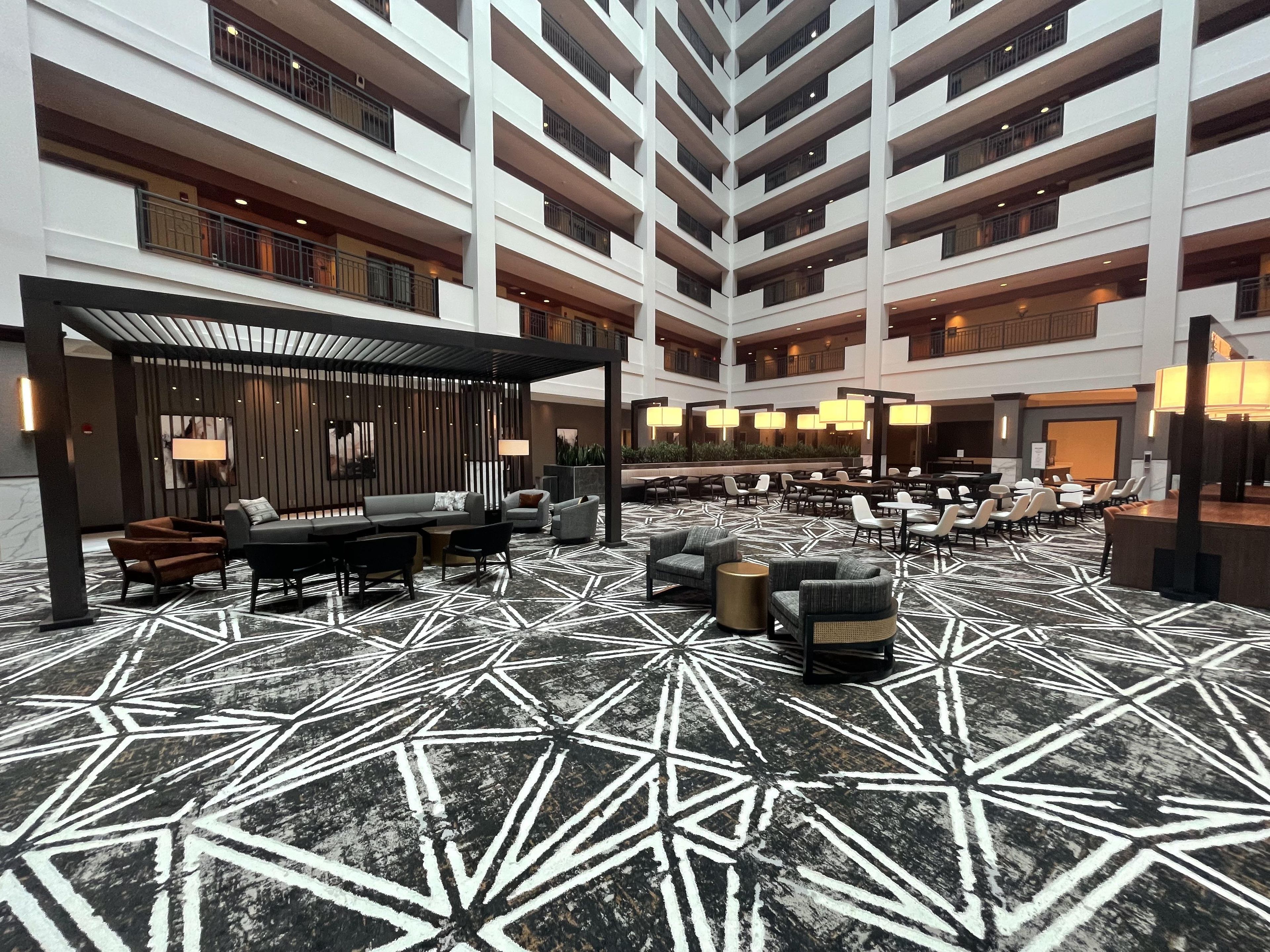 A multi-level hotel lobby with a geometric patterned floor, seating areas, and a modern design.