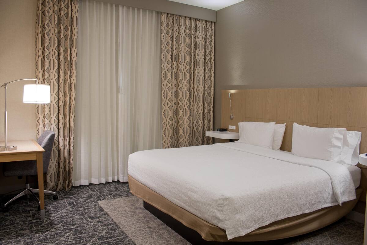 A hotel room with a large bed, a desk, and a chair.