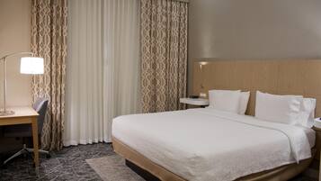 Habitación de hotel con una cama grande, un escritorio y una silla.