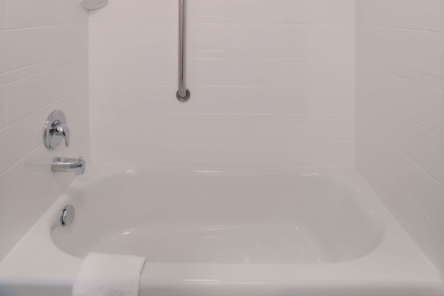 Een moderne badkamer met een badkuip, een handgreep en een waterkraan.