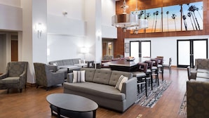 A spacious living area with a sofa, armchairs, a coffee table, and a dining table with chairs. - Hampton Inn Los Angeles-Orange County-Cypress (Cypress)