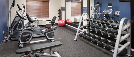 A gym with treadmills, elliptical machines, a bench press, and a rack of dumbbells.