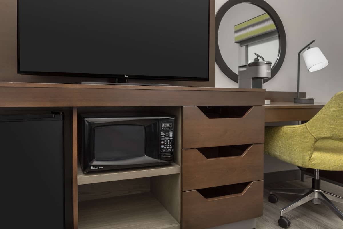 A modern office setup with a flat-screen TV, a microwave, and a desk lamp.