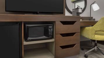 A modern office setup with a flat-screen TV, a microwave, and a desk lamp.