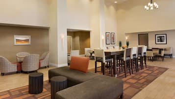 Un amplio vestíbulo de hotel con comedor, diversas opciones de asientos y un candelabro.