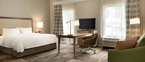 Habitación de hotel con cama, escritorio, silla y televisor.