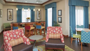 Un vestíbulo de hotel con zonas de estar, un mostrador de recepción y un comedor.
