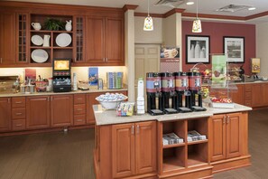 A kitchen with wooden cabinets, a coffee station, and a breakfast bar.