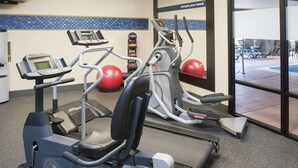Un gimnasio con equipo cardiovascular, una televisión y vistas al exterior.