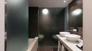 A modern bathroom with two sinks, a bathtub, and a walk-in shower.