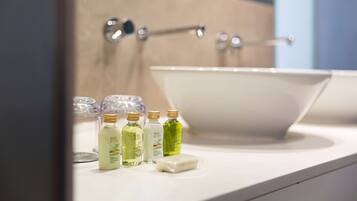 A bathroom with a white sink, a mirror, and three bottles of liquid soap on the counter.
