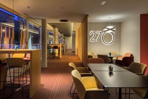 Vestíbulo de hotel con mostrador de recepción, zona de estar y un llamativo letrero con el número '270'.
