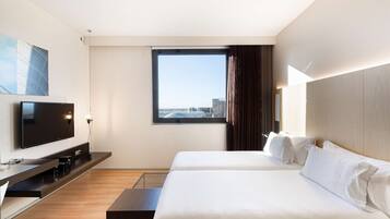 Habitación de hotel con un ventanal grande, televisor de pantalla plana, cama y escritorio.