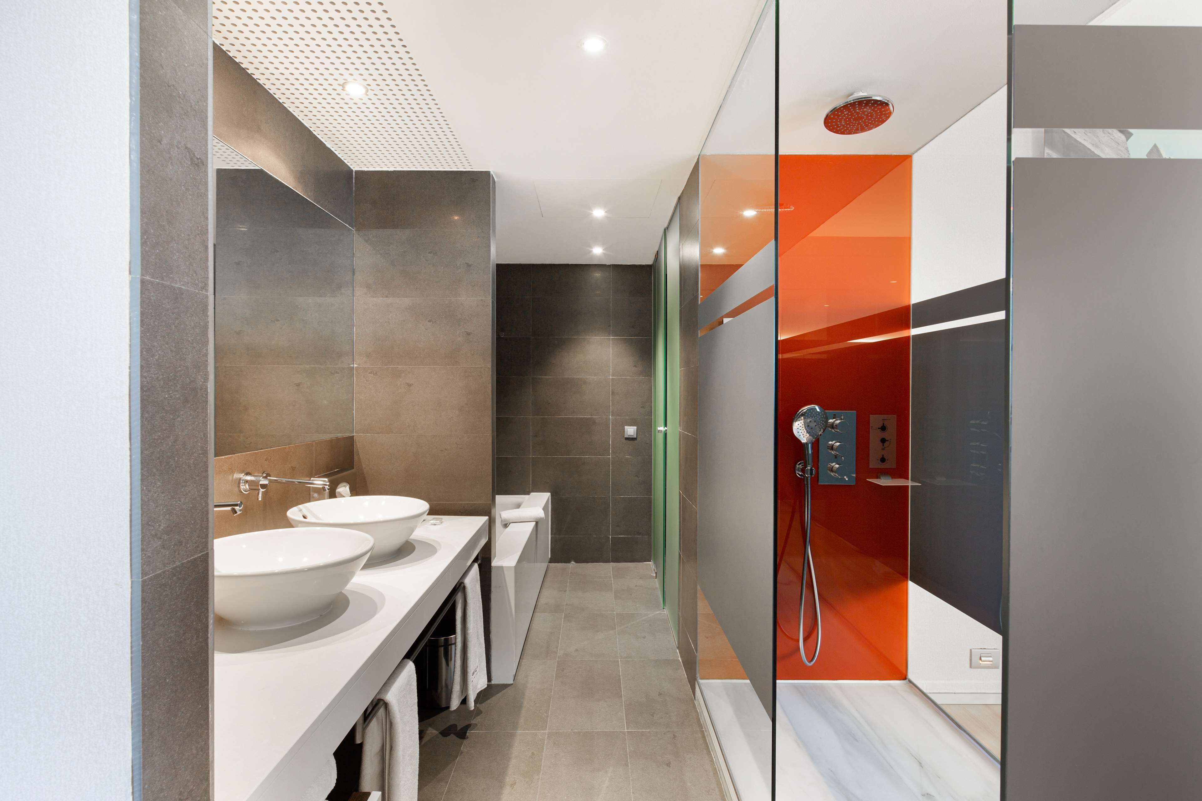 A modern bathroom with two sinks, a shower, and a glass partition.