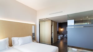 A modern hotel room with a large bed, a glass partition, and a view of the bathroom. - Barcelo Valencia Hotel (Valencia)