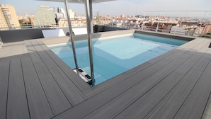 A rooftop swimming pool with a city view, surrounded by a wooden deck. - Barcelo Valencia Hotel (Valencia)