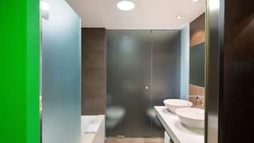 Une salle de bain moderne avec deux vasques, une douche en verre et un mur d’accent vert.
