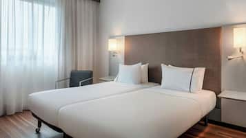 A hotel room with a large bed, two bedside tables, a chair, and a window with curtains.
