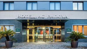 A hotel entrance with a revolving door, potted plants, and signage for 'HOTEL AC PADOVA' and 'AC HOTELS MARRIOTT'. - AC Hotel Padova by Marriott (Padova)