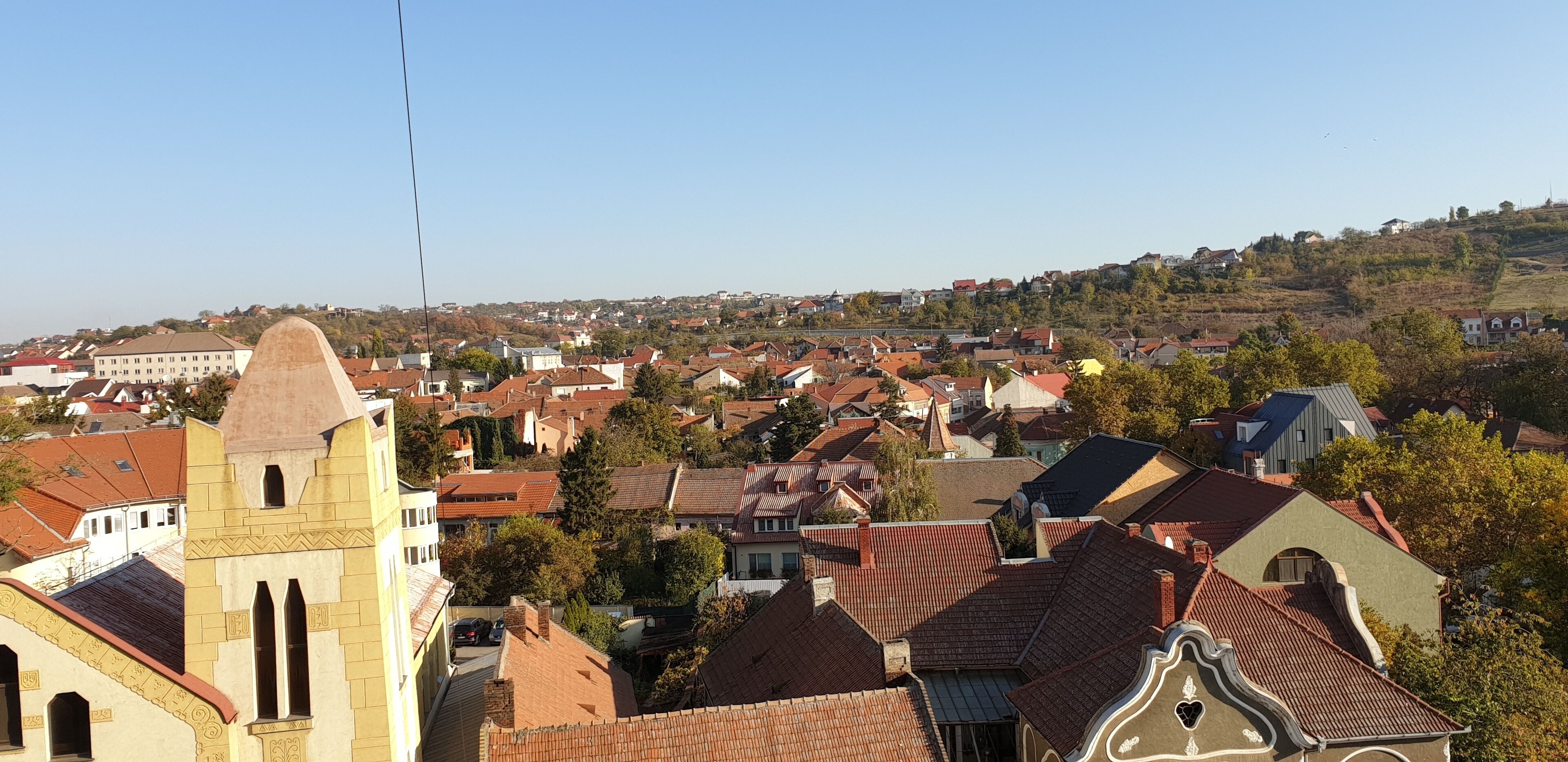 A town with a prominent church tower, surrounded by residential buildings with red-tiled roofs.