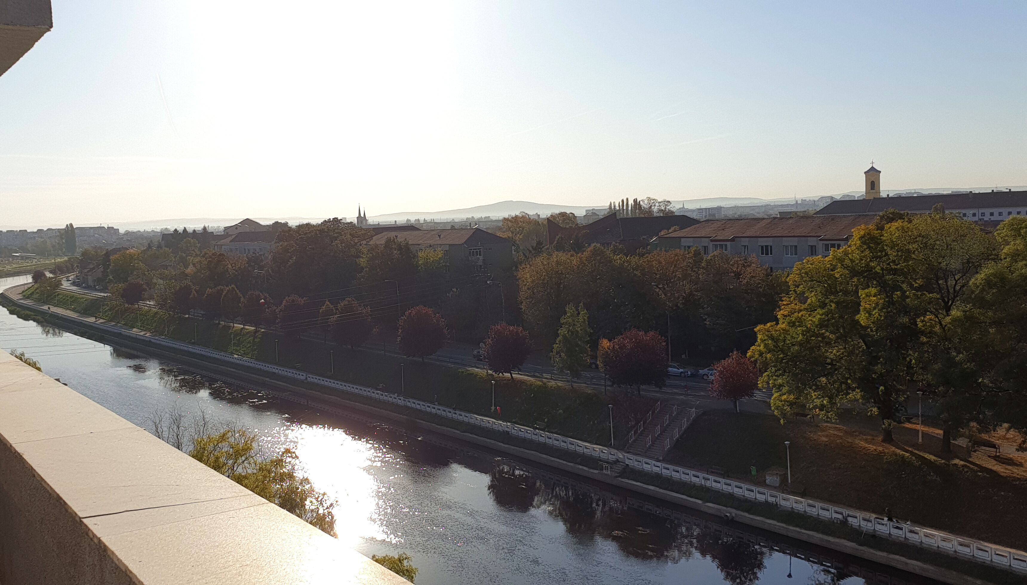 A river with a bridge, trees, and buildings in the background.