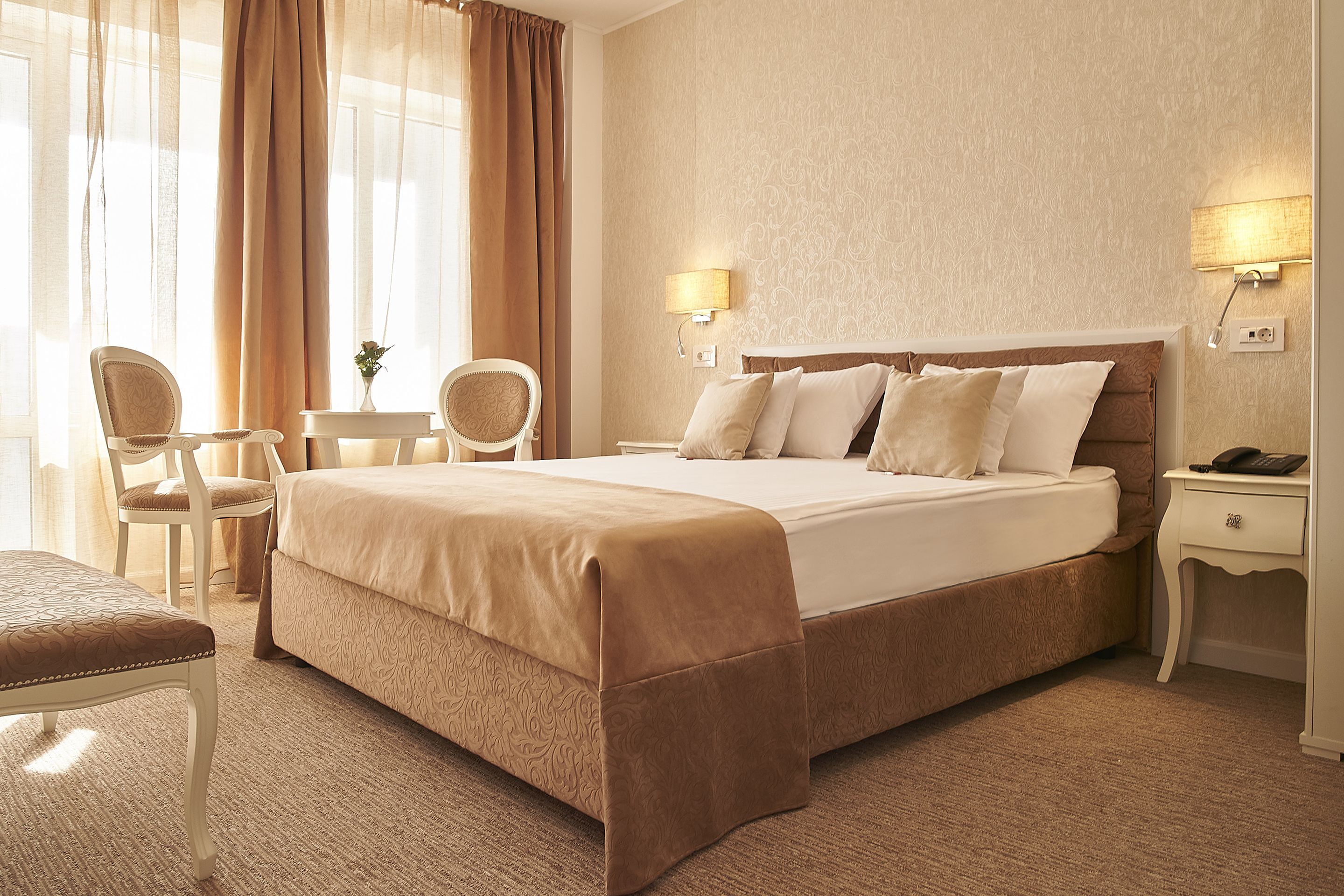 Habitación de hotel con una cama grande, dos mesitas de noche, una silla y una pequeña mesa.