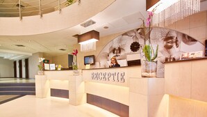 A reception desk with a modern design, a clock, and a vase with flowers. - Continental Forum Oradea (Oradea)