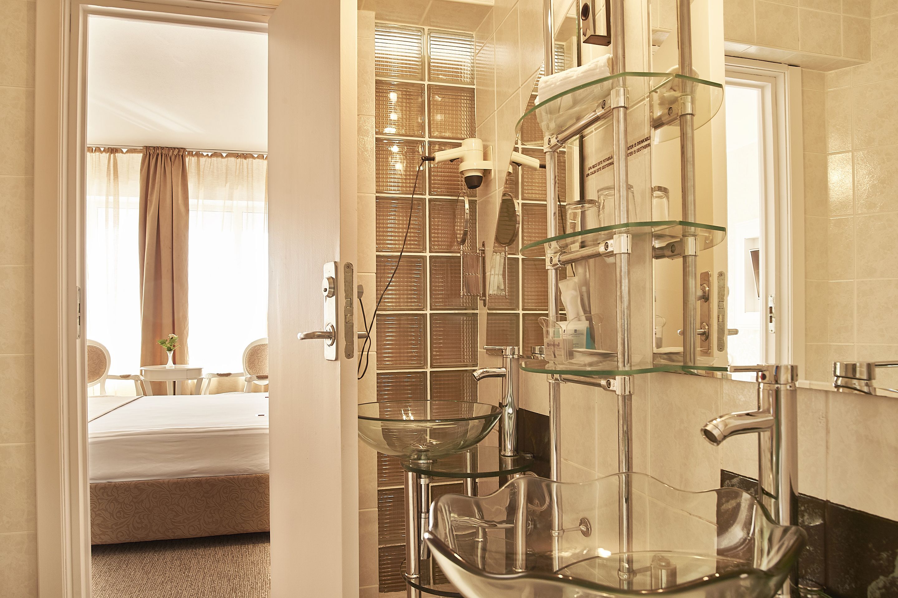 Une salle de bain moderne avec un lavabo en verre, un sèche-cheveux et un miroir.